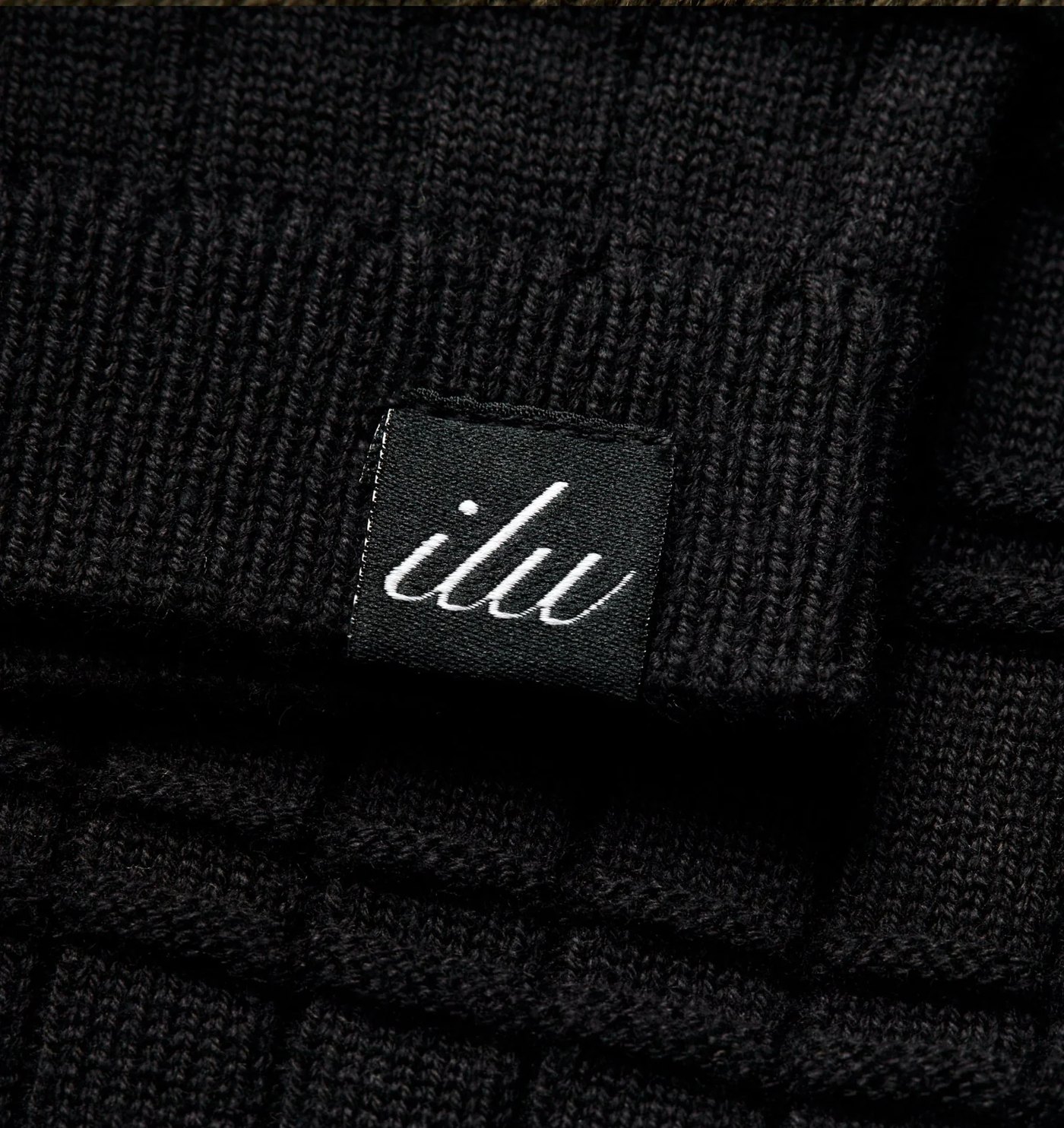 Close-up of the box knit texture and woven script label on the sleeve