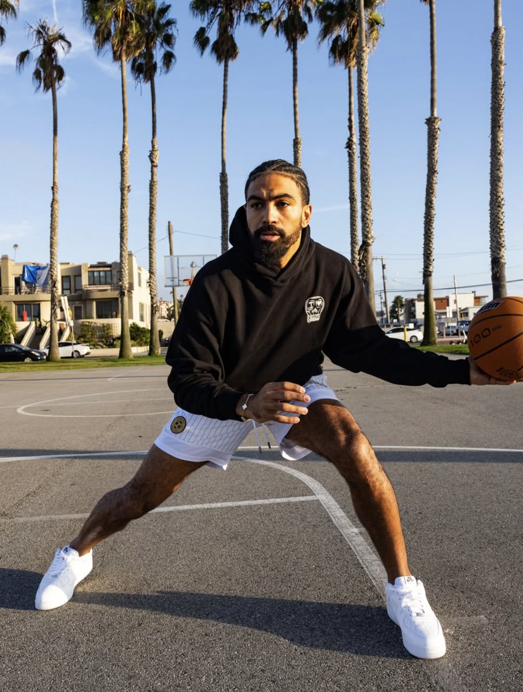 Model dribbling a basketball in the skull hoodie and pinstripe shorts