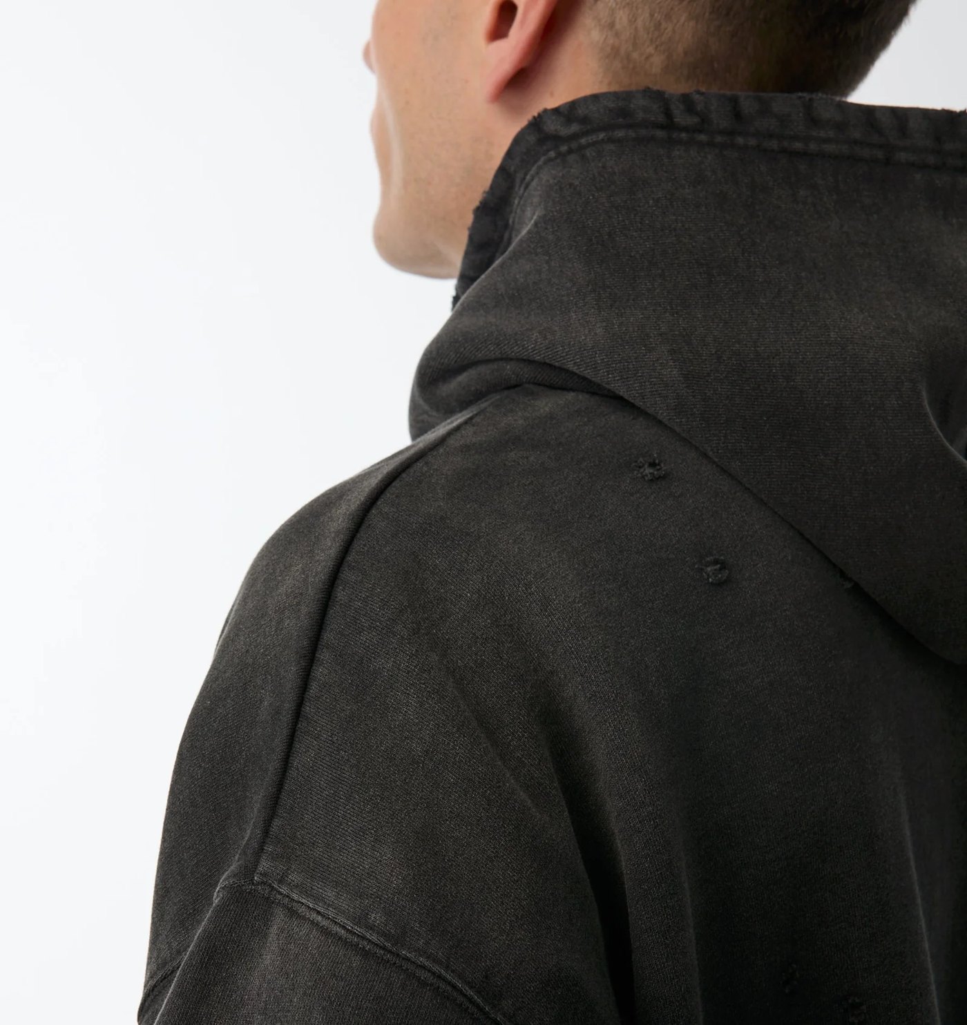 Close-up of the hoodie shoulder showing the faded wash and pinhole distressing