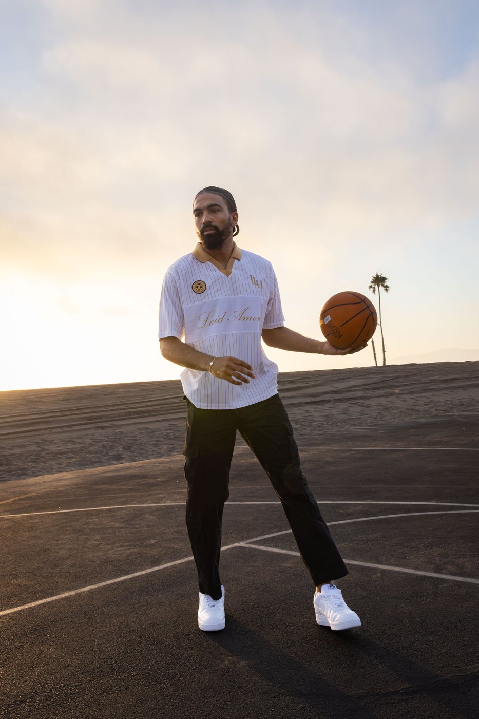 Model holding a basketball on a beach court in the pinstripe Laid Amour jersey
