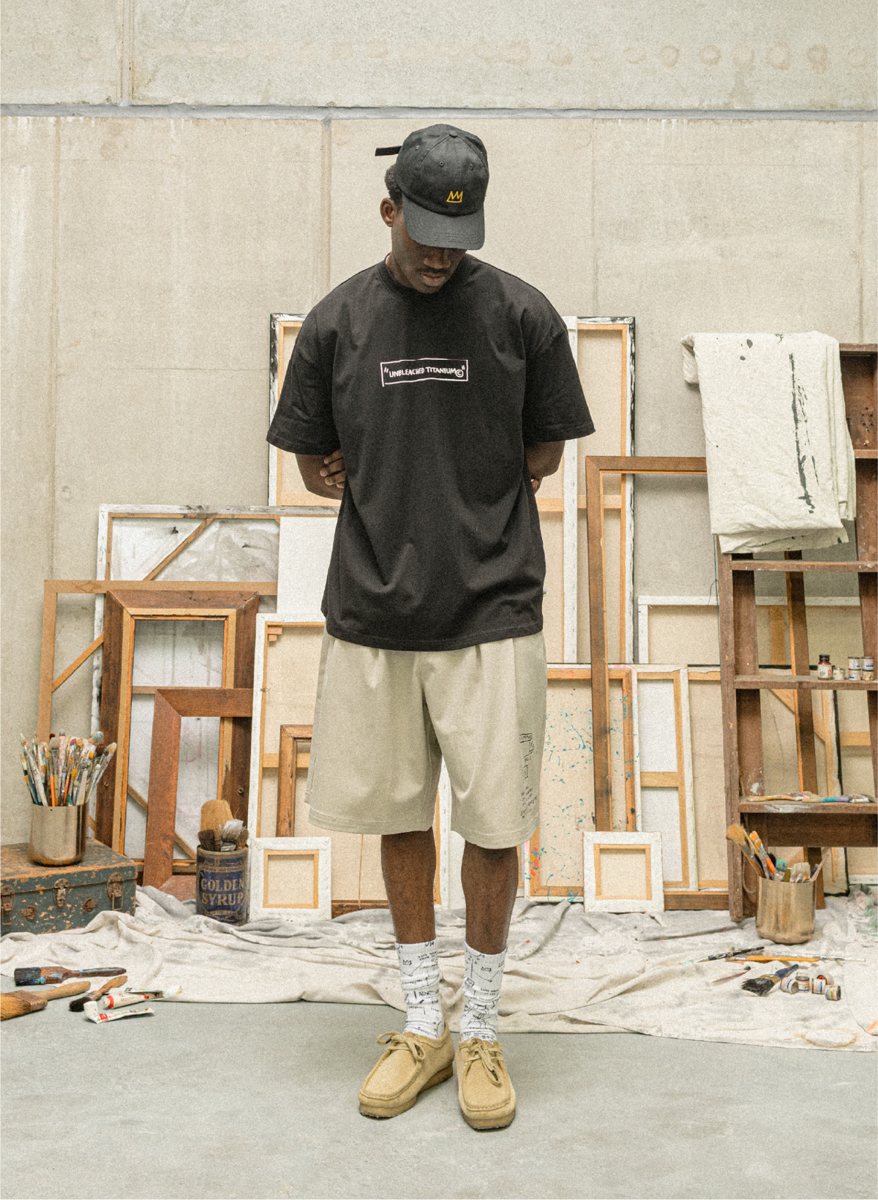 I Love Ugly x Jean-Michel Basquiat: Black graphic tee with stone shorts and printed socks