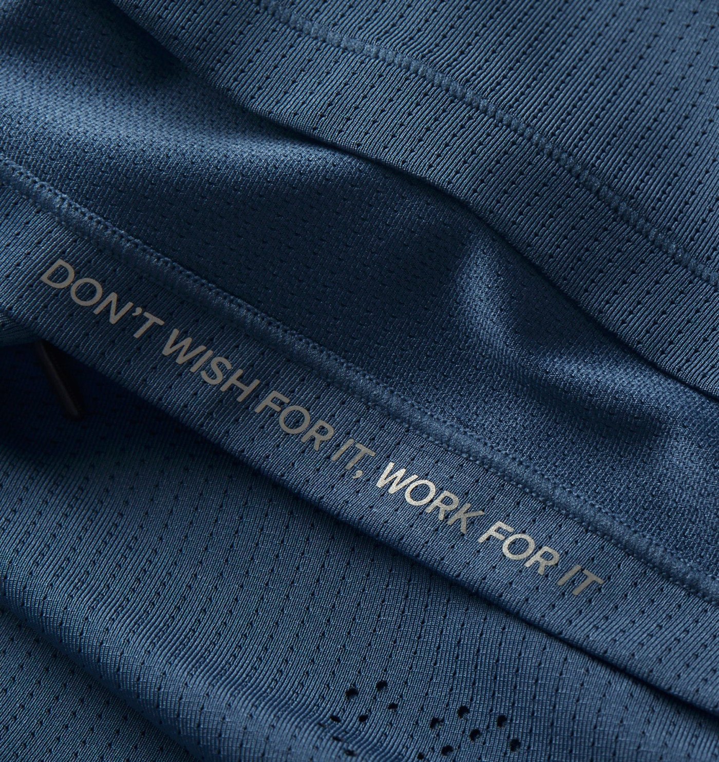 Close-up of the mesh jersey, laser perforation and reflective slogan print