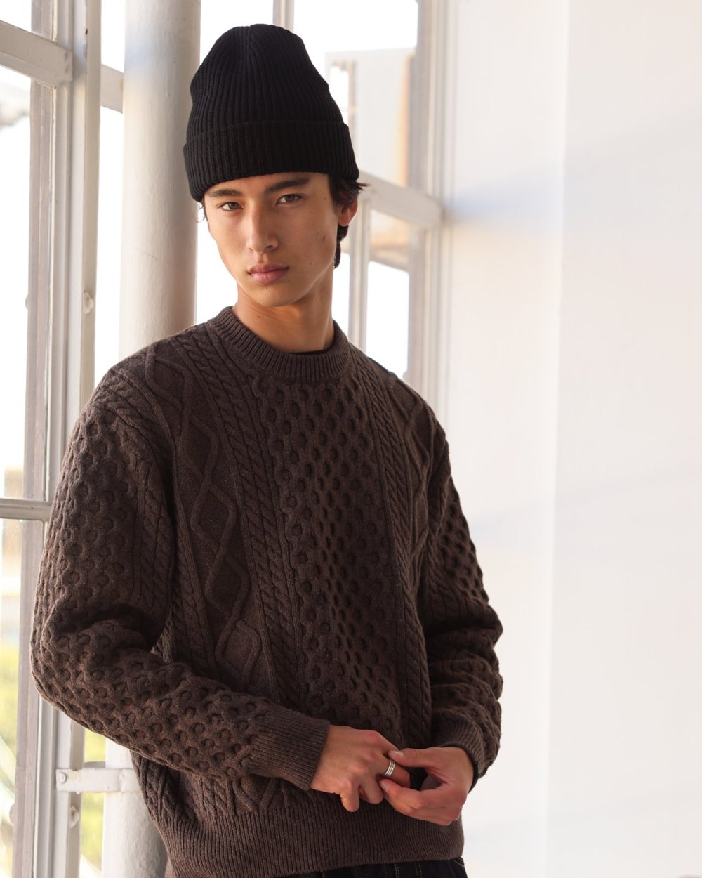 Brown marl cable knit crewneck sweater worn with a black beanie