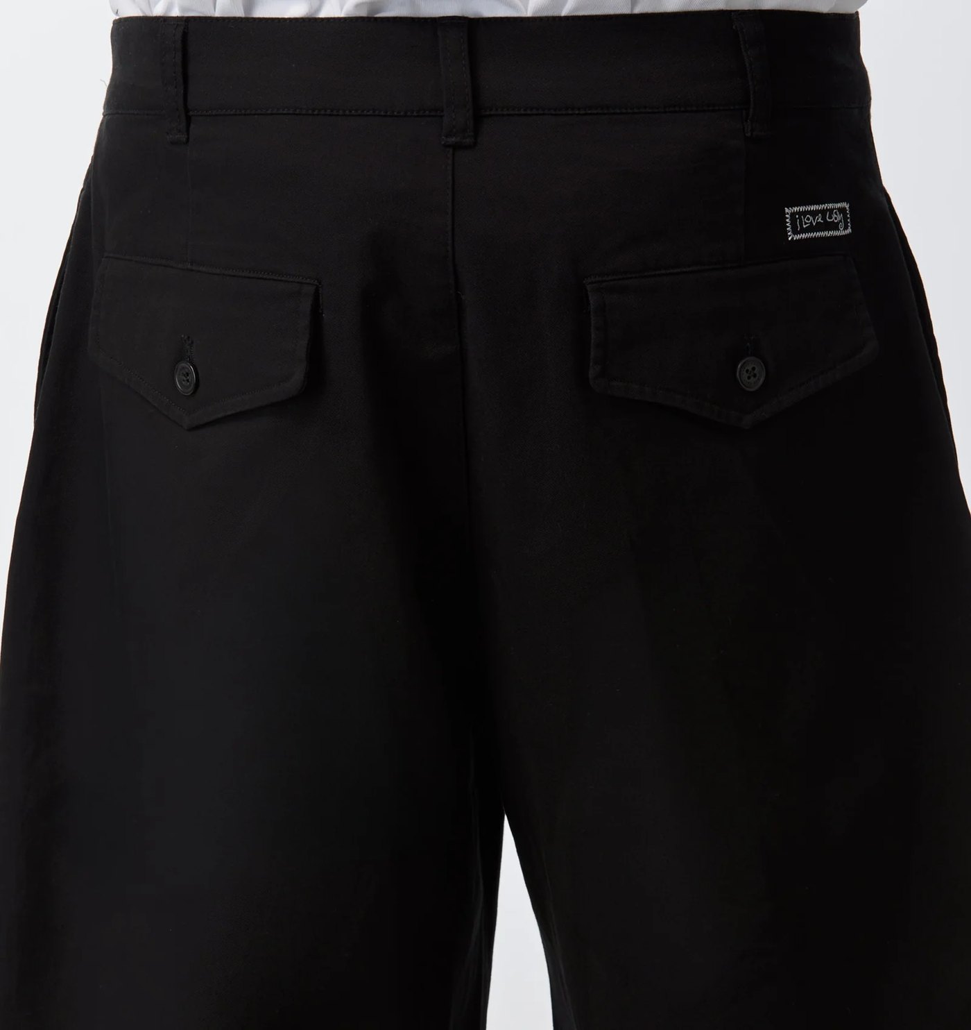 Back of the barrel leg pant showing buttoned flap pockets and woven label