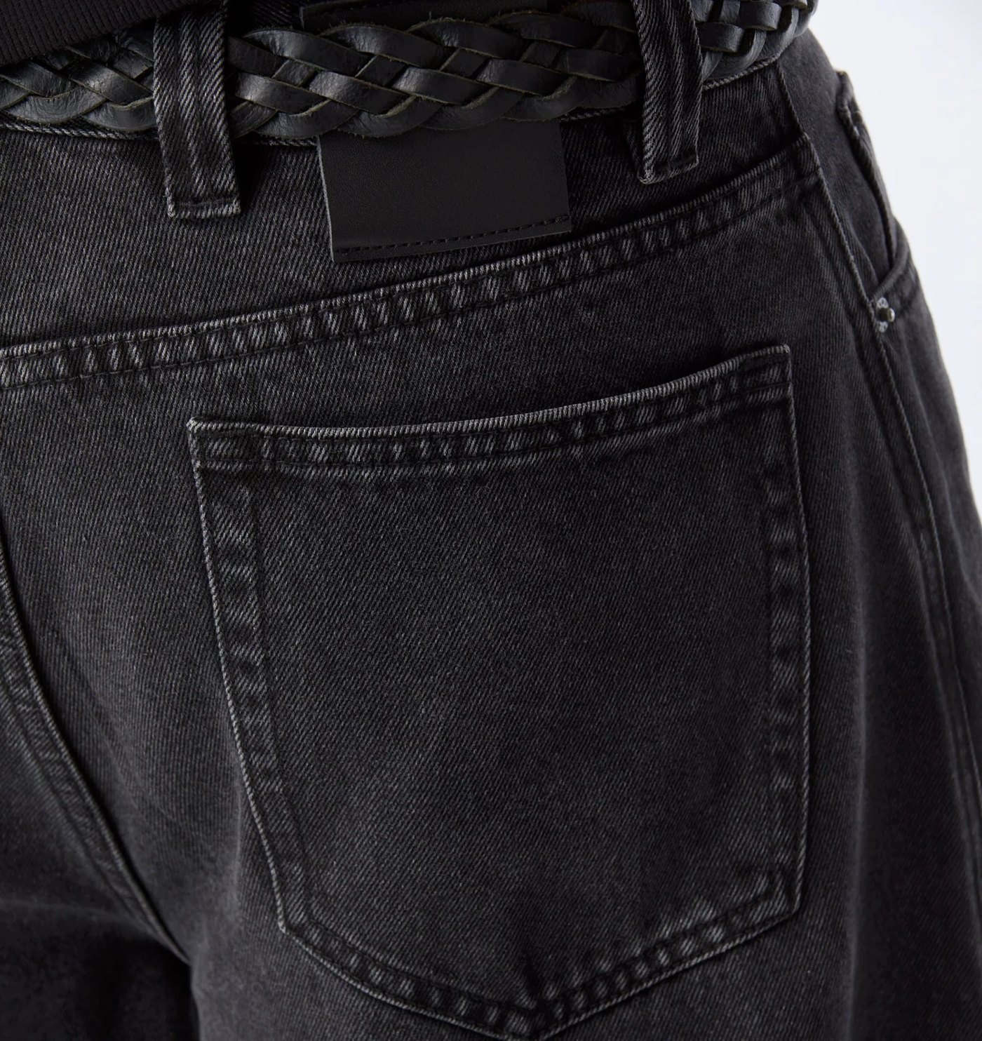 Close-up of the back pocket and black leather patch on the washed black denim