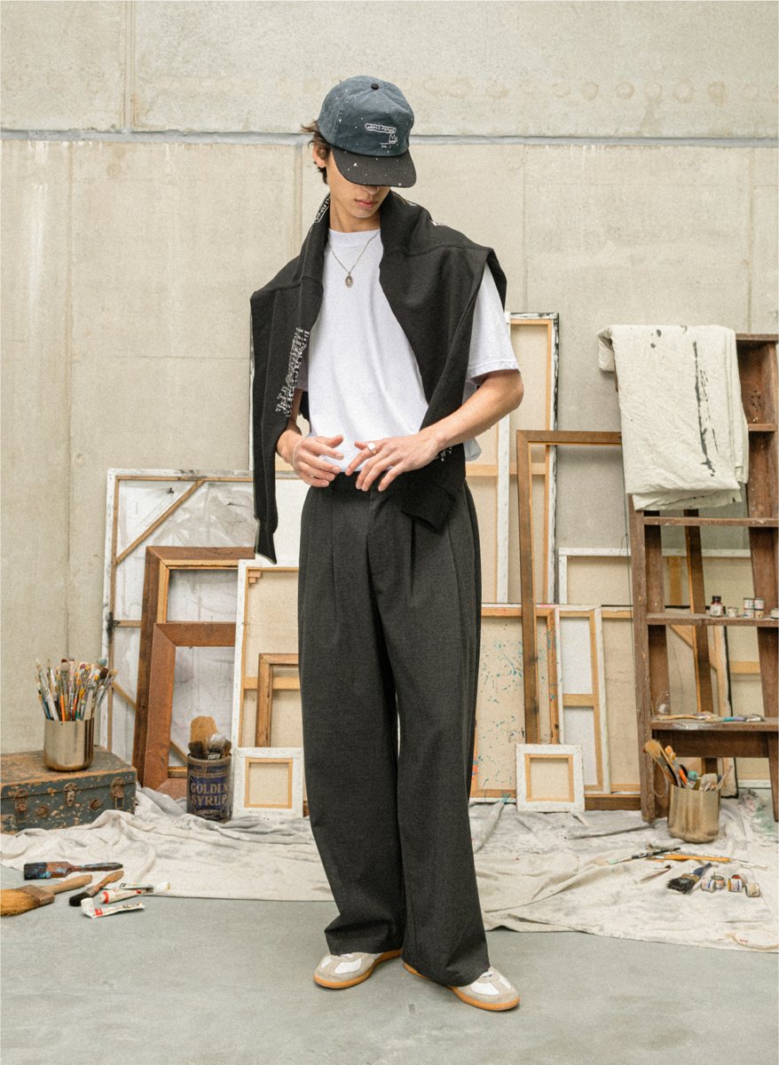 I Love Ugly x Jean-Michel Basquiat: Charcoal pleated trousers with a printed sweat tied over the shoulders