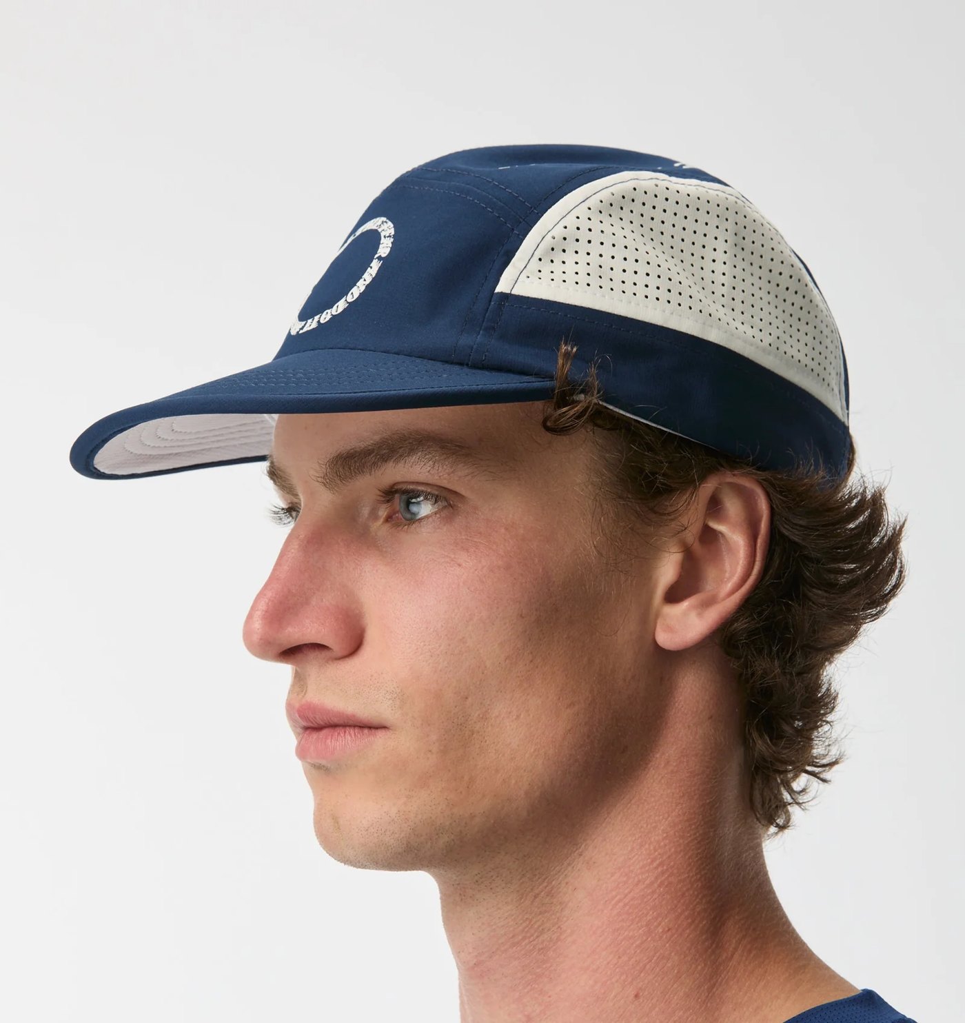 Side profile of the navy five panel cap showing the perforated white panel