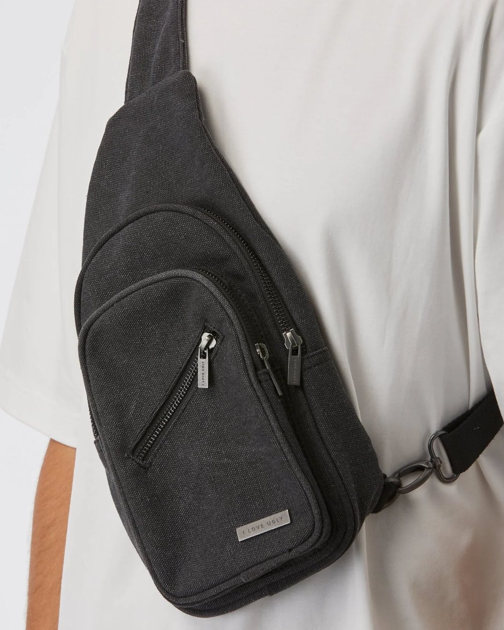 Washed black canvas sling bag worn across the chest