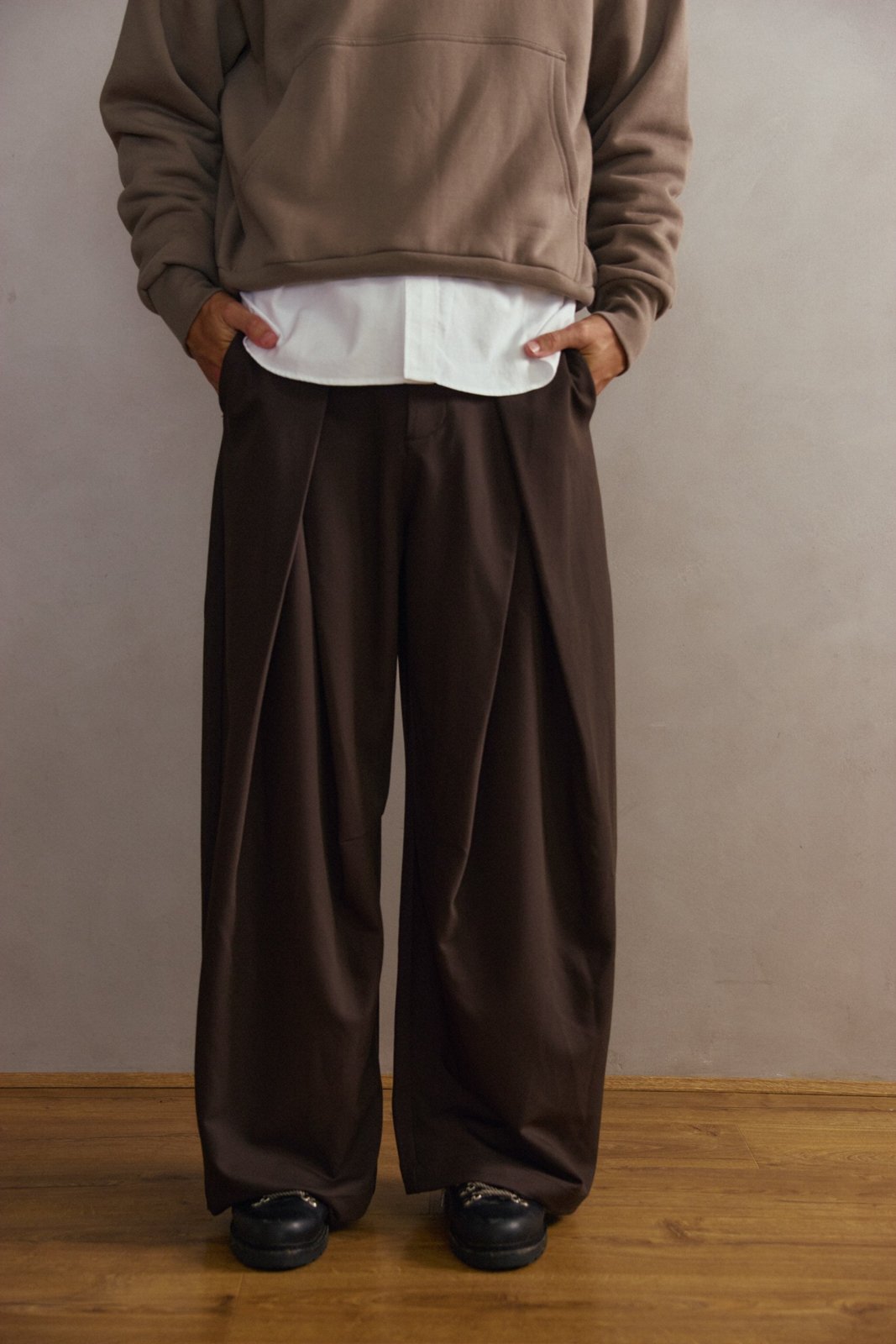Wide-leg brown pleated trousers worn with a taupe cropped hoodie over a white shirt