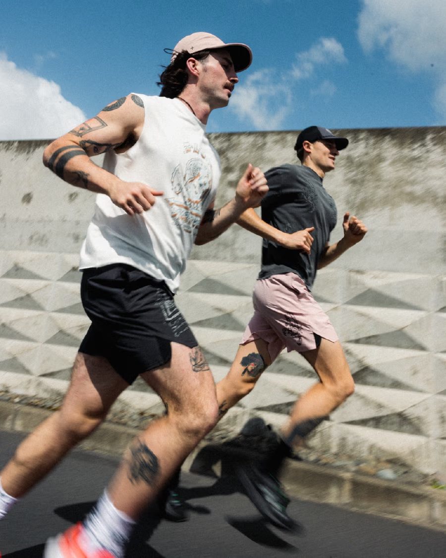 Two runners on a city street in Rebel Yuth running singlets, tees and shorts