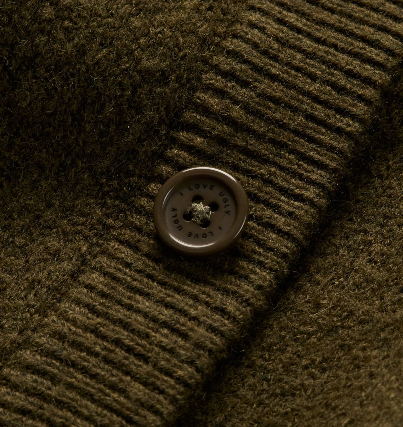 Close-up of the alpaca knit, ribbed placket and engraved button