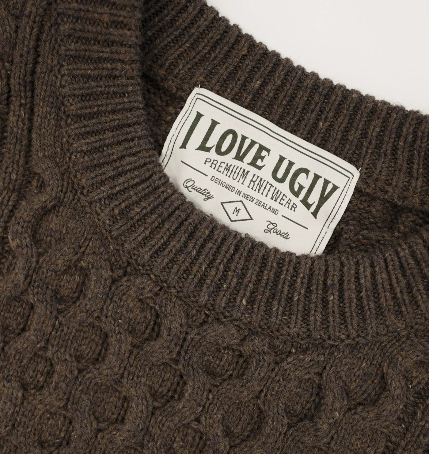 Close-up of the cable knit, ribbed crew neck and Premium Knitwear neck label