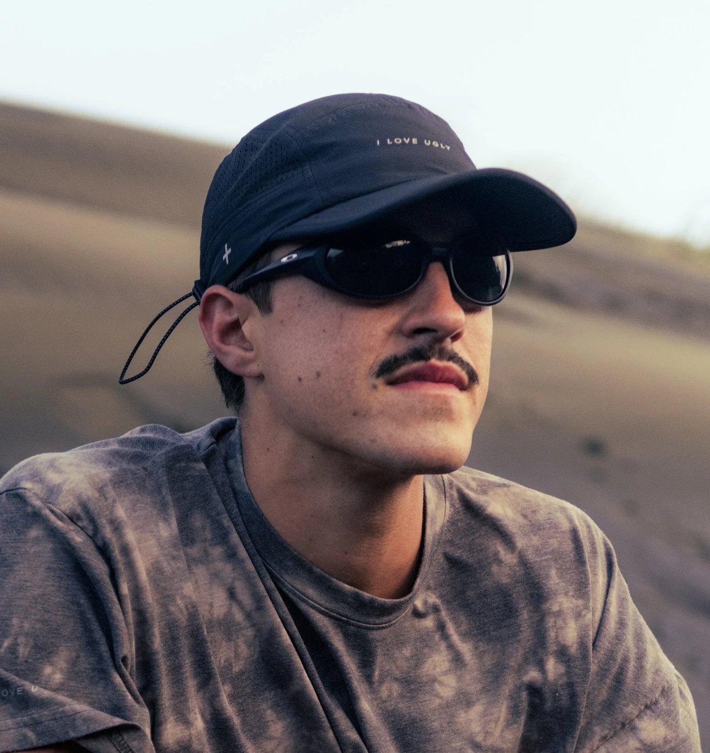 Black active five panel cap worn outdoors on the dunes