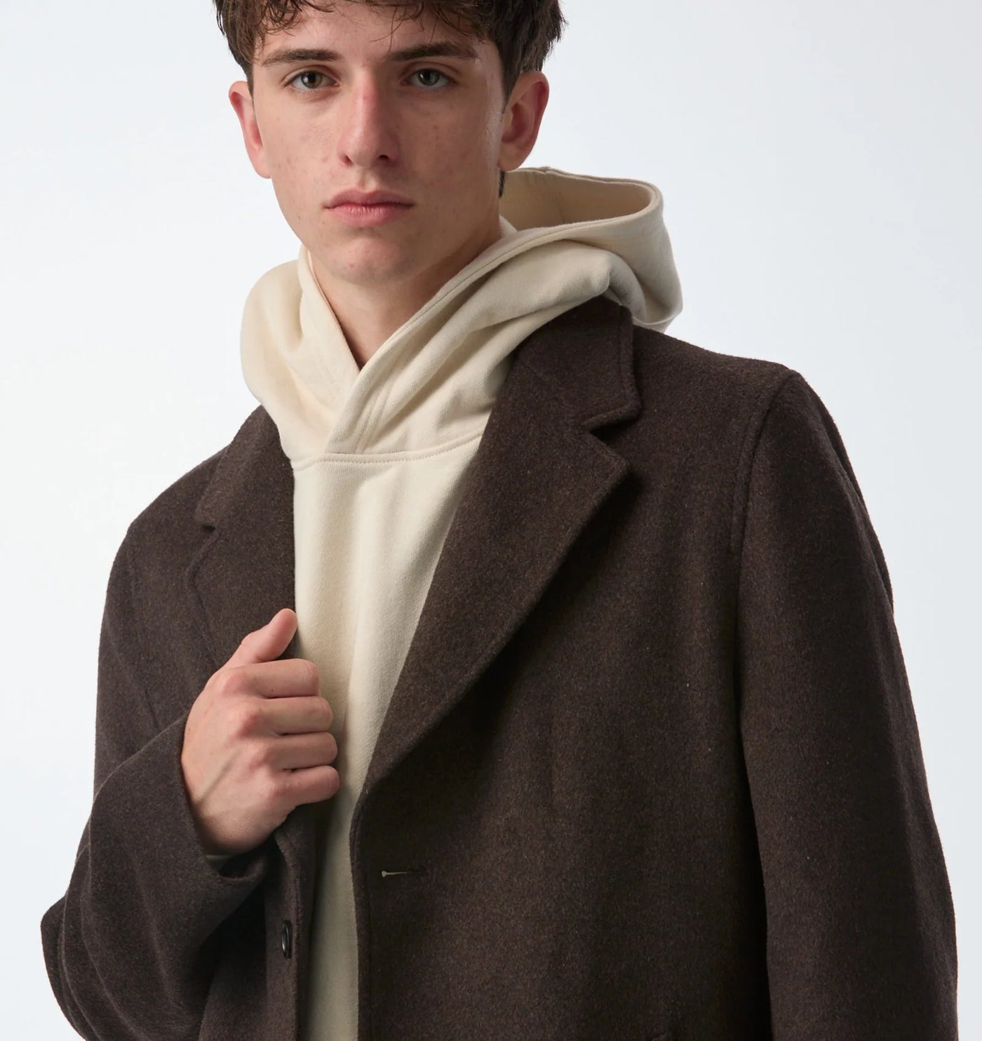 Close-up of the brown wool overcoat lapel worn over a cream hoodie