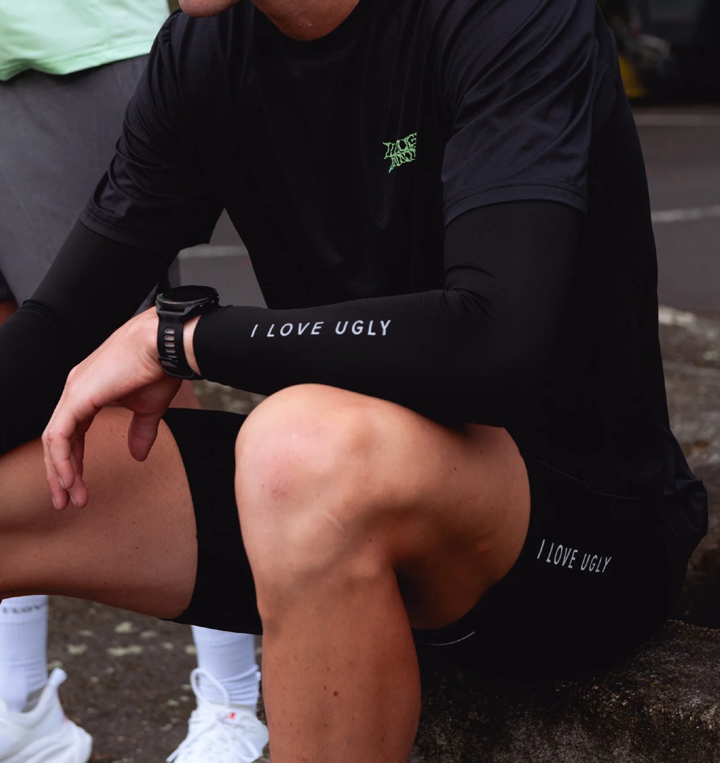 Black compression arm sleeves with wordmark worn by a seated runner