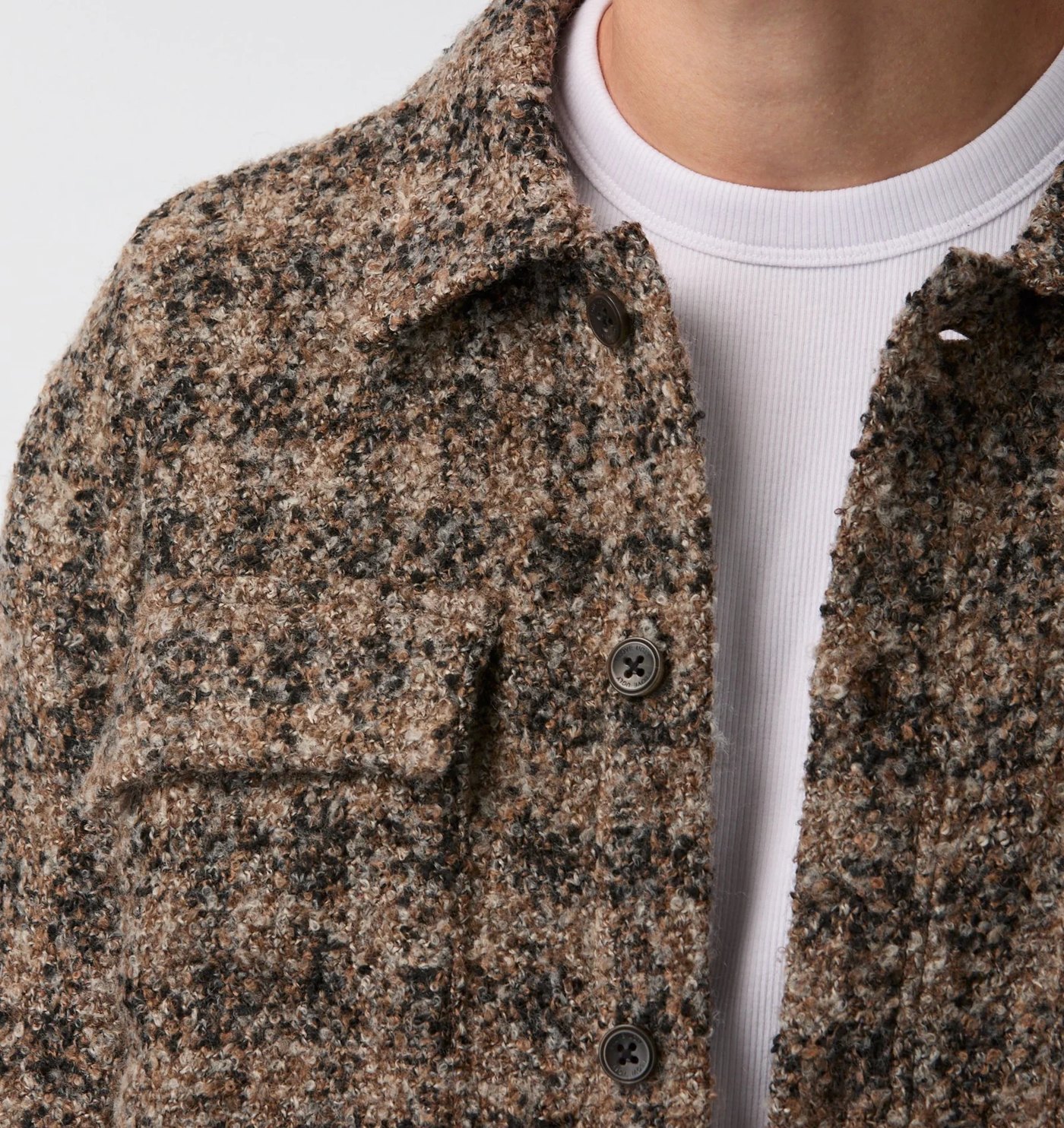 Close-up of the bouclé collar, flap pocket and branded buttons