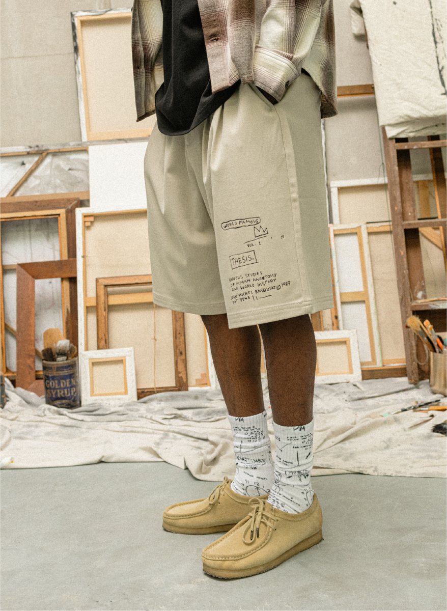 I Love Ugly x Jean-Michel Basquiat: Stone shorts with the Basquiat THESIS print, worn with printed socks