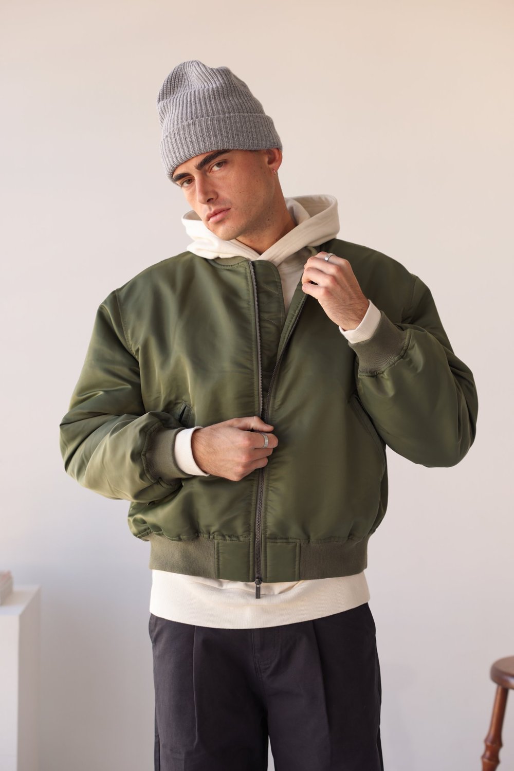 Olive nylon bomber jacket over a cream hoodie