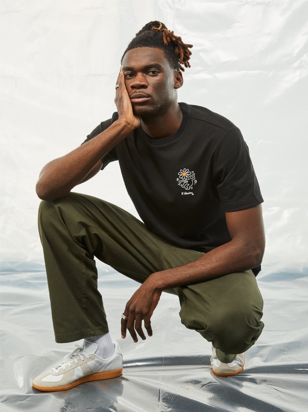 I Love Ugly x Keith Haring: Black graphic tee with olive pants, crouching
