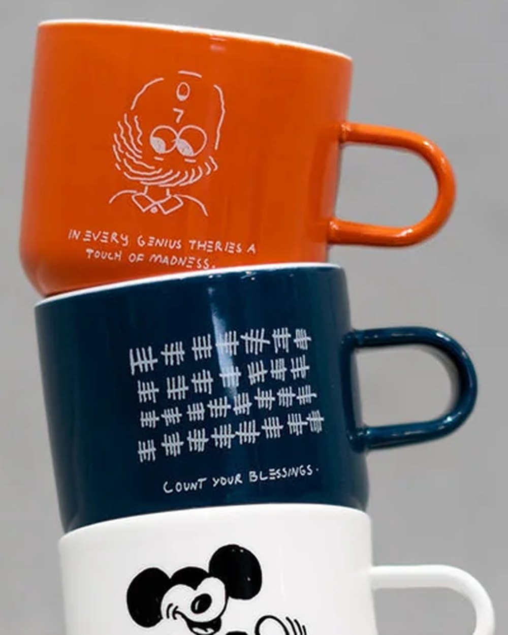 Close up of the illustrated orange and navy mugs