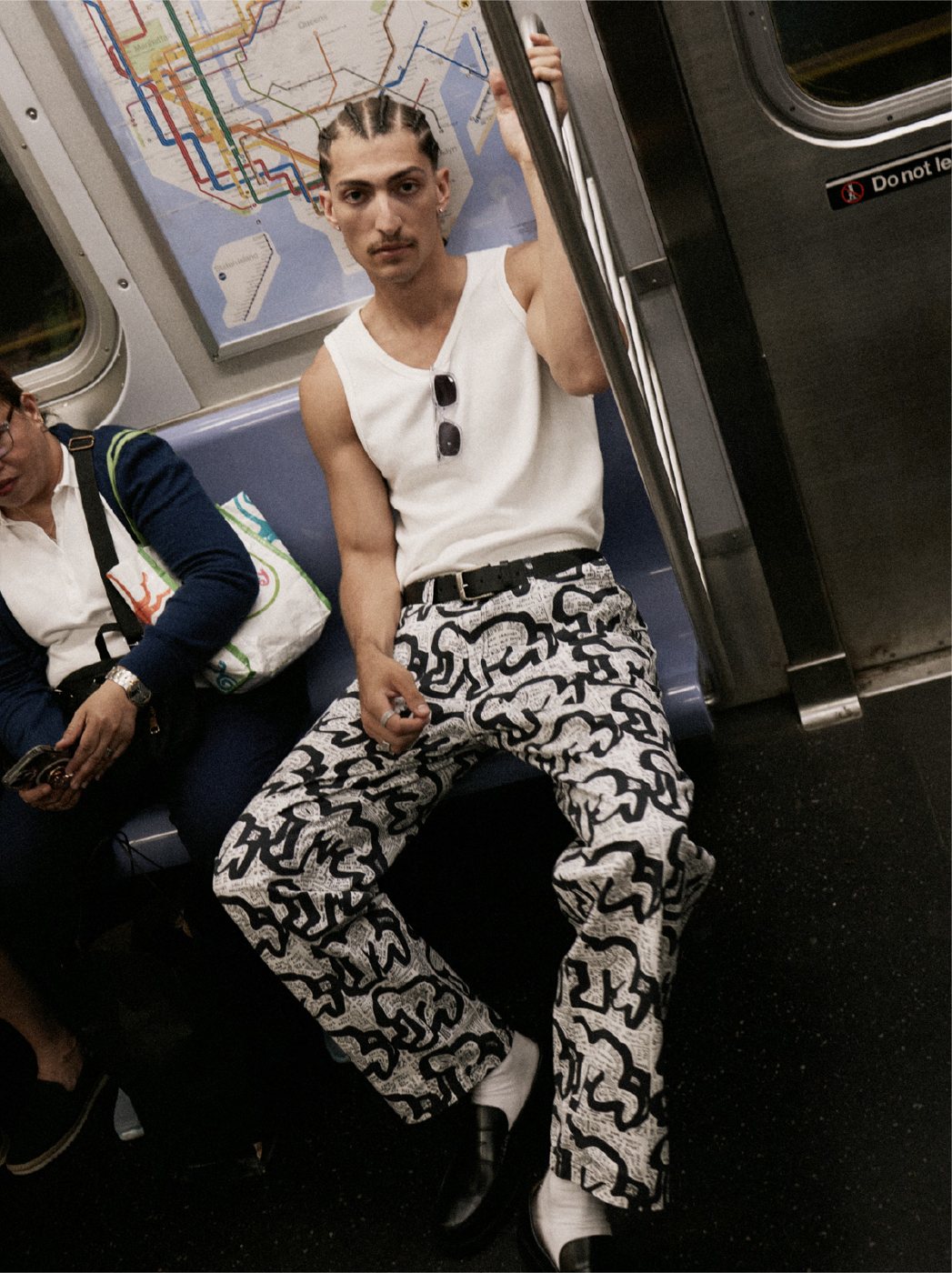 I Love Ugly x Keith Haring: White tank and Keith Haring print pants on the subway